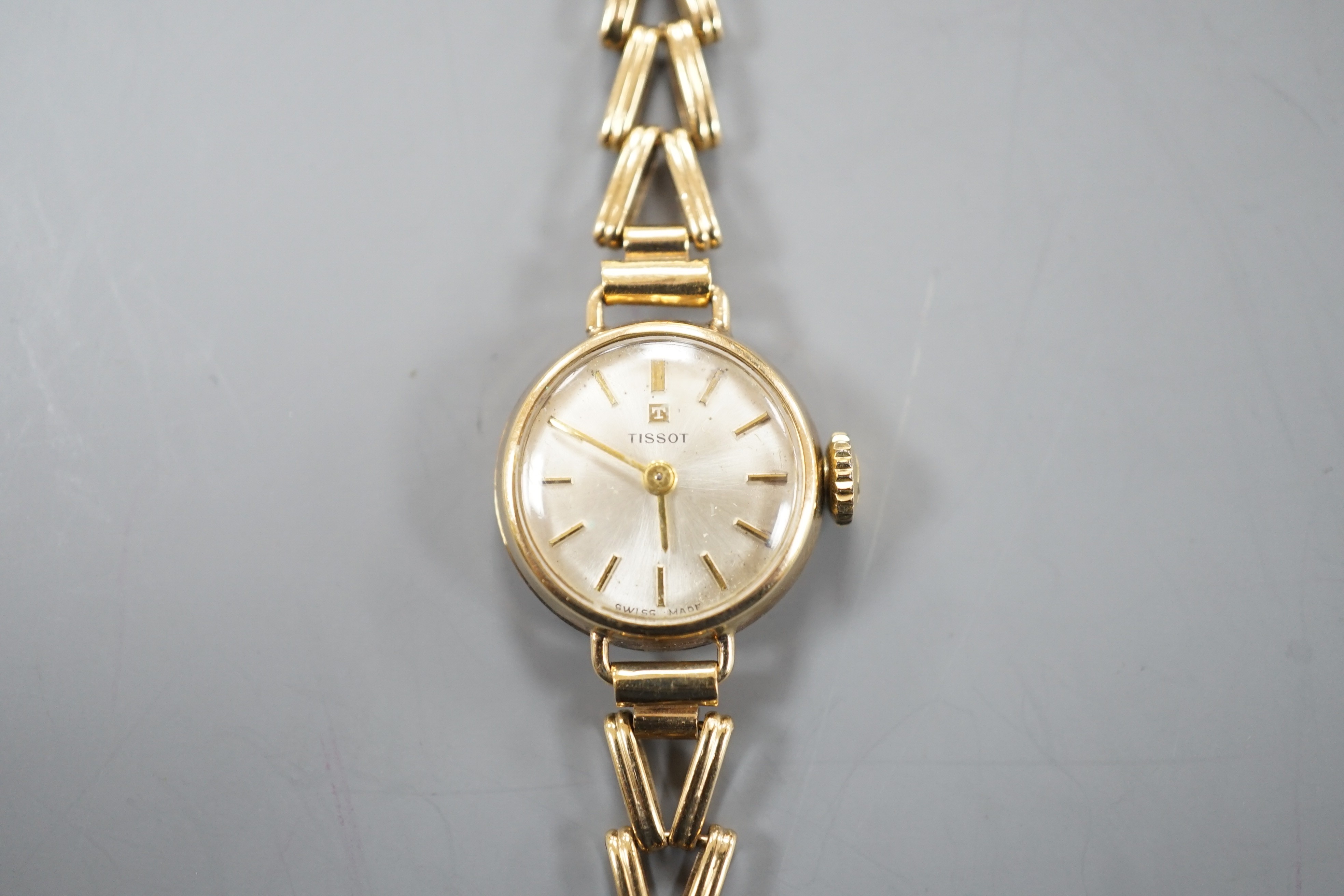A lady's 9ct gold Tissot manual wind wrist watch, on a 9ct gold bracelet, overall length 16.25cm, gross weight 11.2 grams.